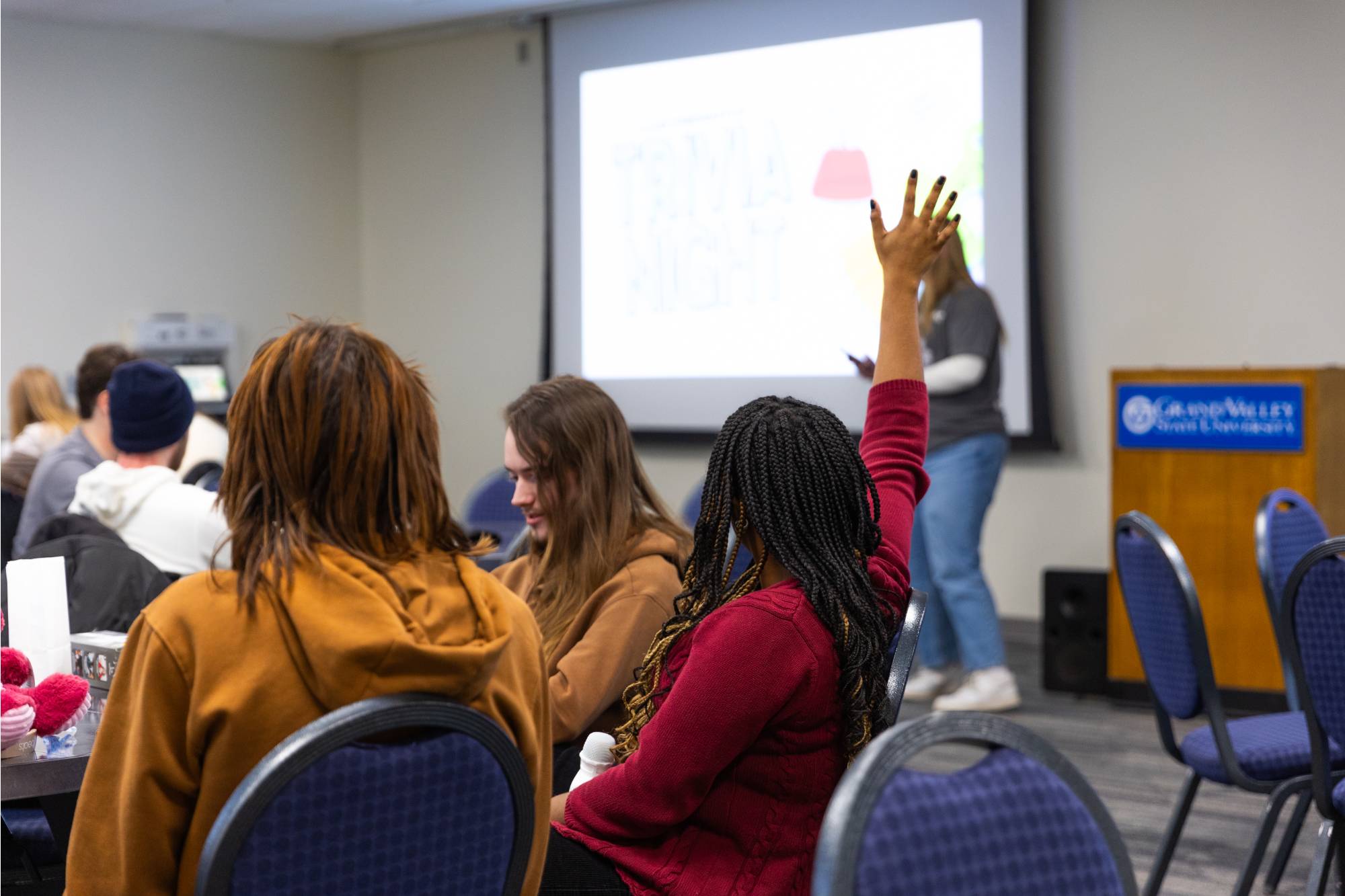Girl raises her hand at trivia to answer a question